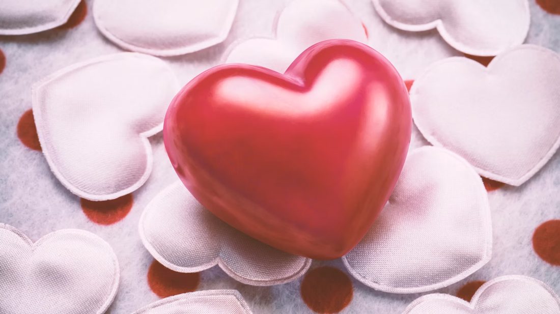 A red heart resting on white satin hearts